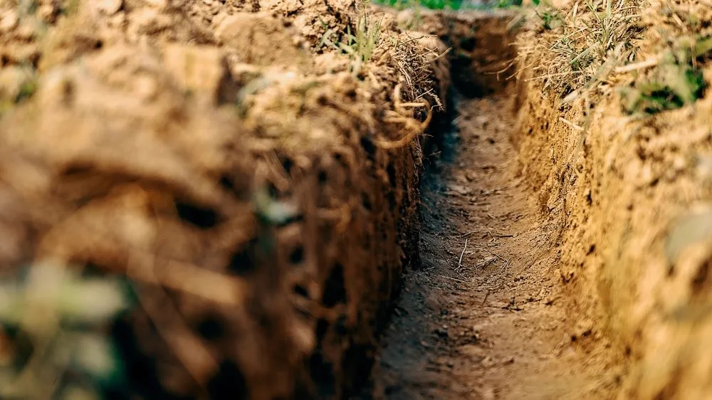 Freshly excavated drainage trench cut through soil ready for new pipework