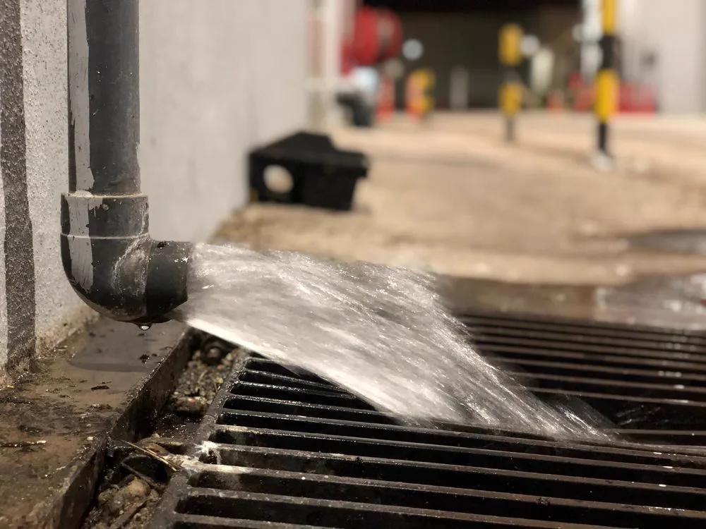 Stormwater rushing across a grated drainage inlet after heavy Brisbane rain