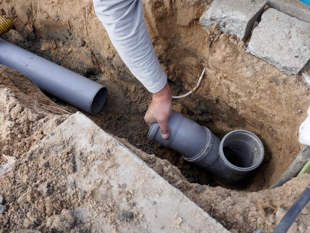 Drainer working on a damaged drain pipe in the ground ready for pipe relining